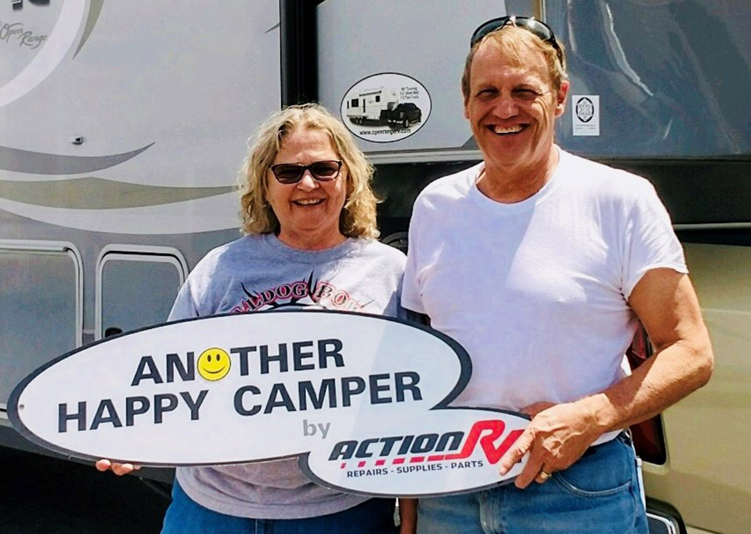 Two customers holding an Action RV Another Happy Camper sign
