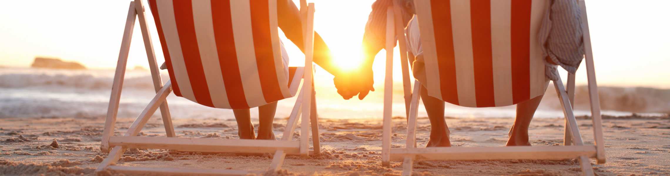 Couple holding hands in beach chairs at sunset